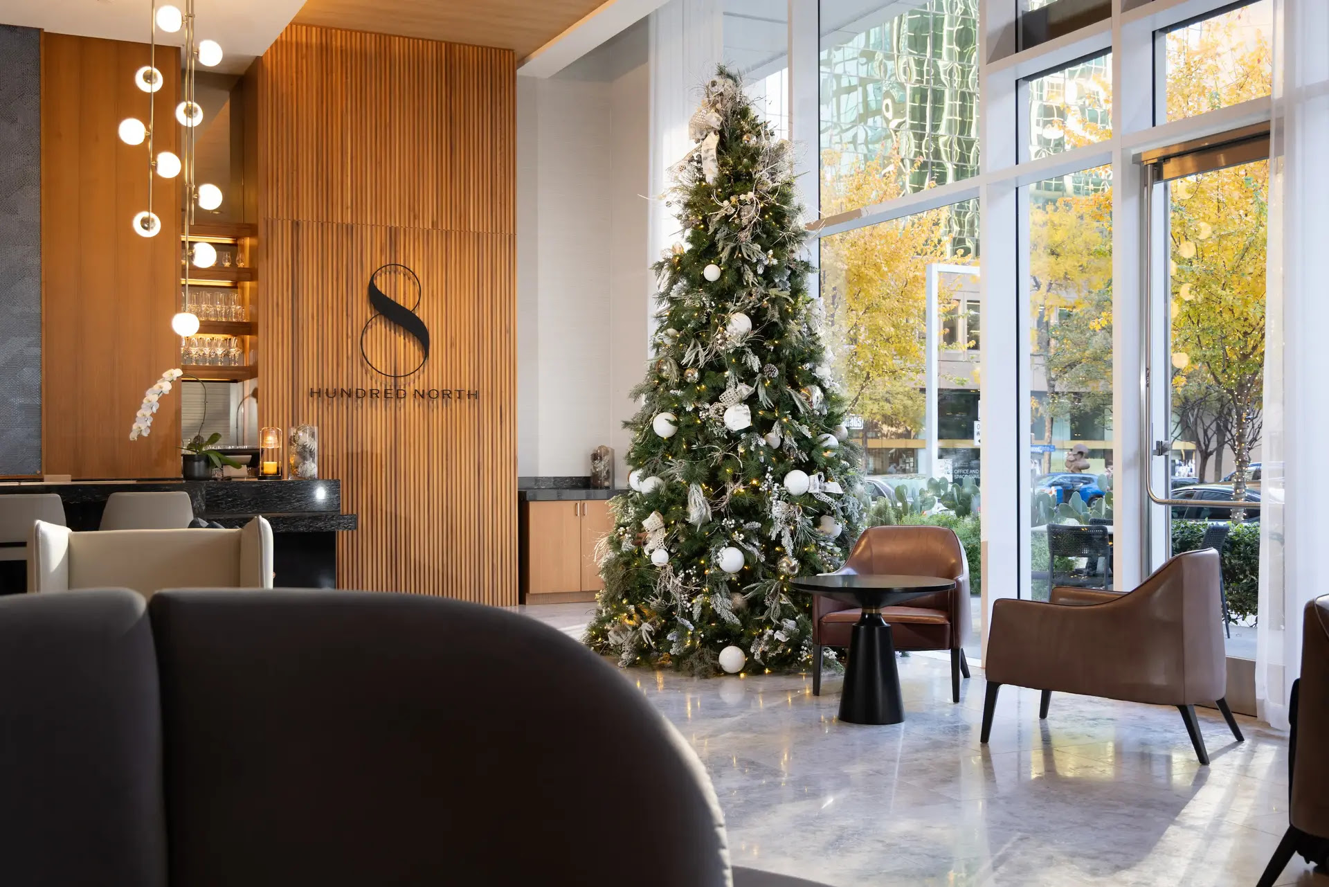 Commercial atrium decorated for the holidays with a tall lit tree and layered garland